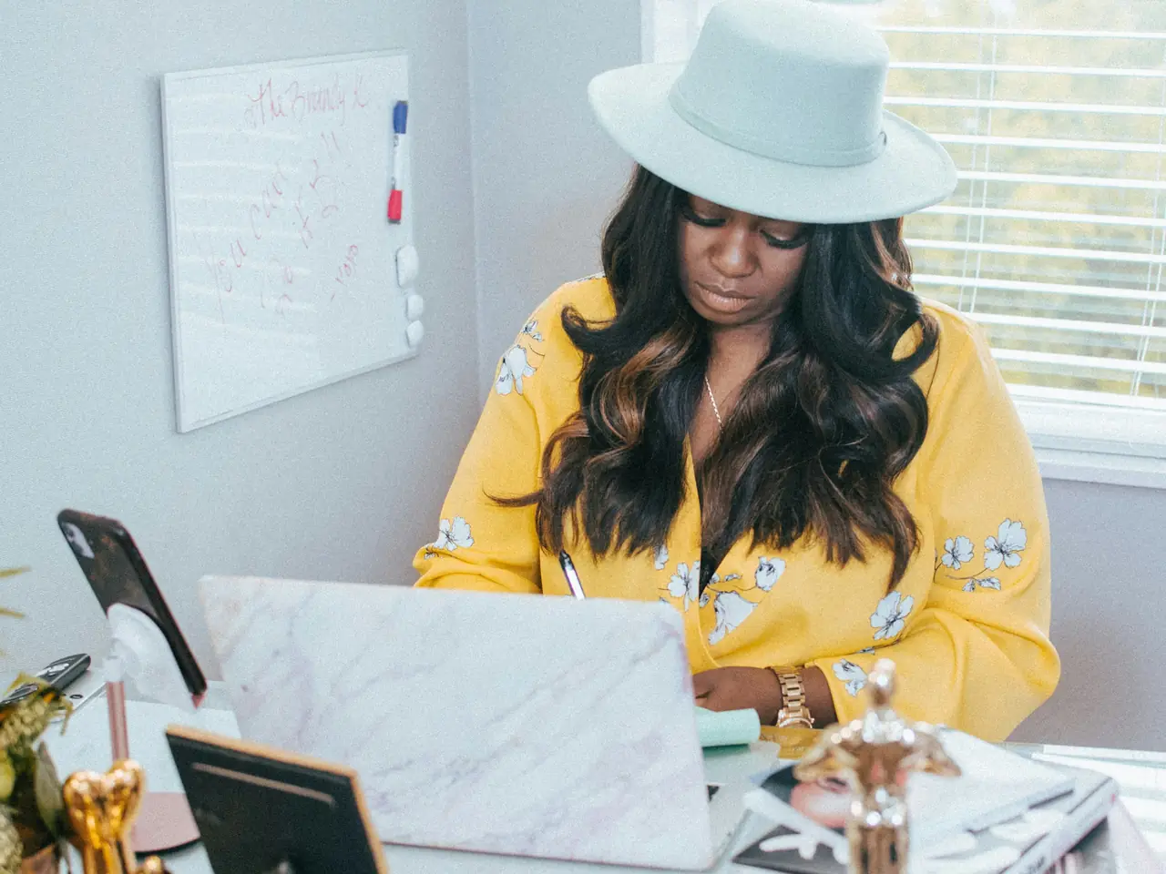 A freelancer at her desk with a laptop open, writing notes